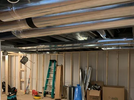 Spiral trunk ductwork and branch takeoffs running through a framed basement ceiling