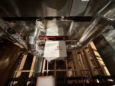 Whole-home dehumidifier tied into spiral ductwork between the floor joists