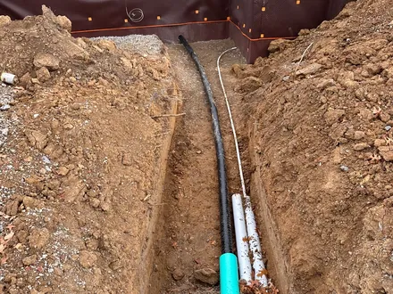 Utility trench carrying conduit and piping to a newly poured foundation