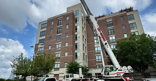Crane lifting HVAC equipment at a multi-story Cincinnati commercial building
