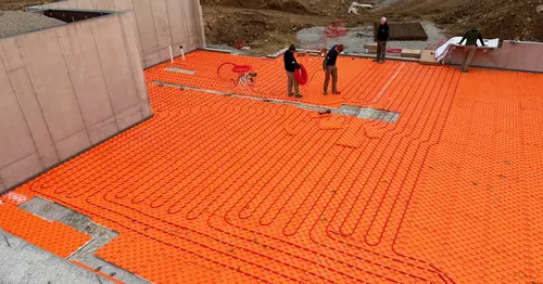 Pinnacle Air Solutions technicians installing radiant floor heating tubing on a new foundation slab