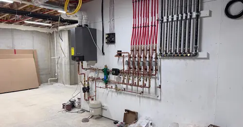 Finished mechanical room with boiler, manifold and copper piping installed by Pinnacle Air Solutions