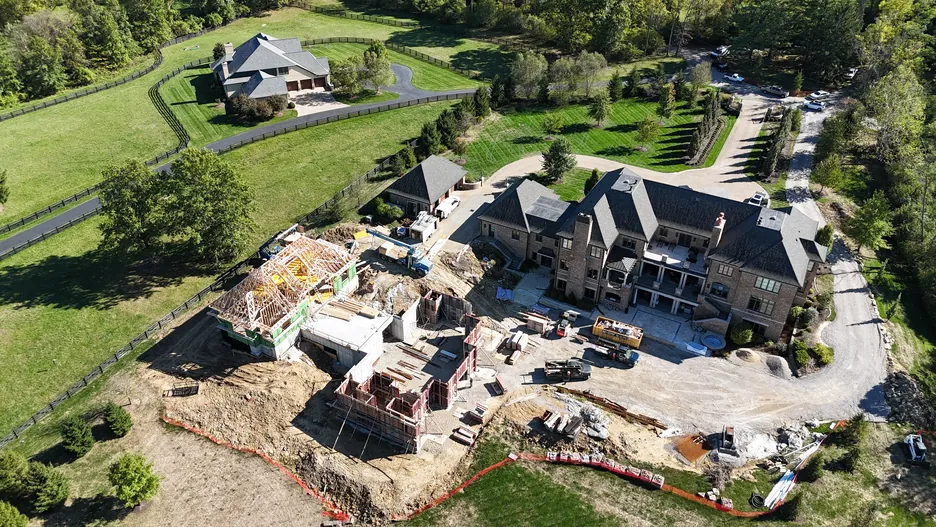 Aerial view of a large custom home under construction near Cincinnati with framing and site work underway
