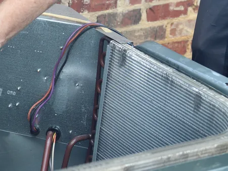 Close-up of a heat pump's copper refrigerant lines and electrical connections during a maintenance inspection