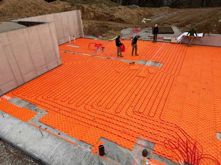 Close-up of PEX radiant floor tubing loops laid across a foundation slab before the concrete pour
