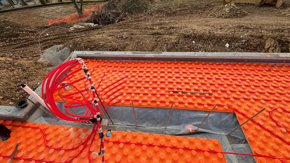 Radiant heating manifold rough-in visible through wall framing during construction