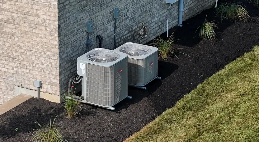 Two Bryant central air conditioning condensers installed beside a brick Cincinnati home by Pinnacle Air Solutions