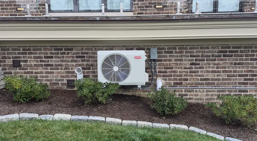 Bryant heat pump outdoor unit wall-mounted on a brick Cincinnati home by Pinnacle Air Solutions